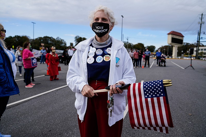 In this Nov. 15, 2020, file photo a supporter waits to hear Georgia Democratic candidate for U.S. Senate Jon Ossoff and Raphael Warnock speak during a rally in Marietta, Ga. (AP Photo/Brynn Anderson, File)