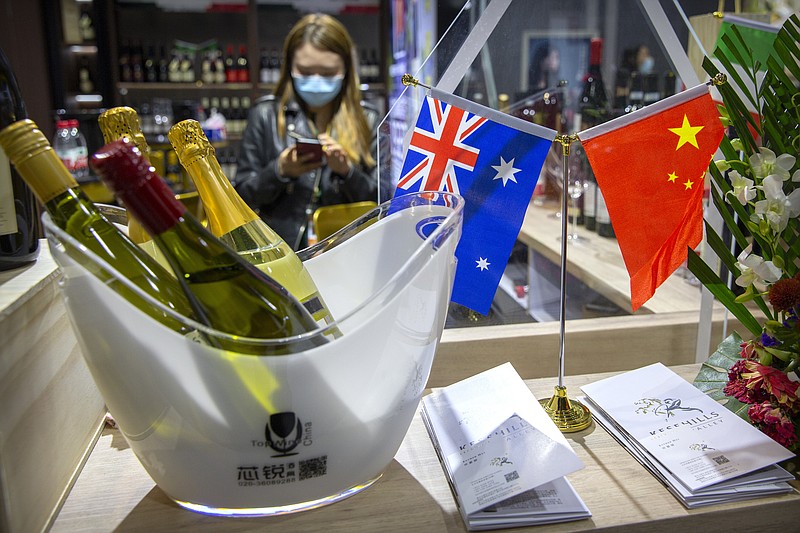 A staff member wearing a face mask stands near a display of Australian wines at the China International Import Expo in Shanghai, Thursday, Nov. 5, 2020. Chinese leaders are conducting an import fair under intensive anti-coronavirus controls in their latest effort to revive the world's No. 2 economy while the United States and Europe struggle with a renewed surge of infections. (AP Photo/Mark Schiefelbein)