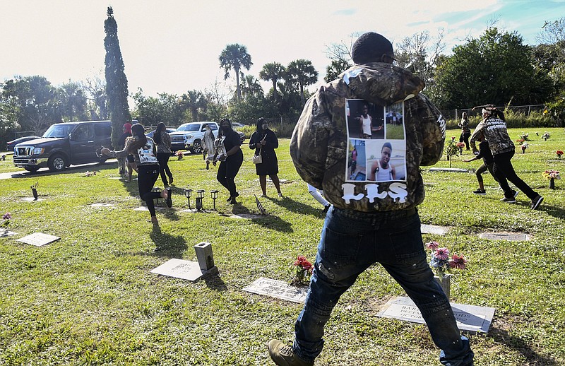 Spectators run from the scene after a shot was fired during the burial service of Sincere Pierce at Riverview Memorial Gardens in Cocoa, Fla., Saturday, Nov. 28, 2020. Pierce was one of two teens shot and killed by a Brevard County Sheriff's deputy on Nov. 13. (Craig Bailey/Florida Today via AP)