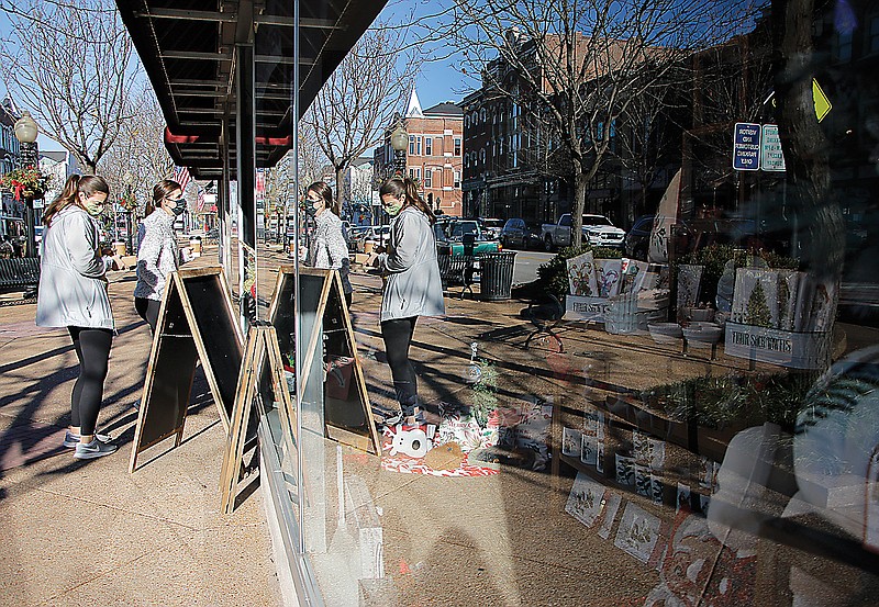 Shoppers enter Carrie's Hallmark, reflected in the windows, on a sunny Saturday in downtown Jefferson City.