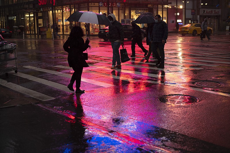 Shoppers walk in a rainstorm, Monday, Nov. 30, 2020 in New York. With people staying home as virus cases surge, Cyber Monday is expected to be the biggest online shopping day yet, bringing in nearly $13 billion in one day. (AP Photo/Mark Lennihan)