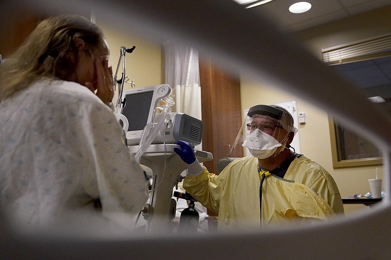 Dr. Shane Wilson kneels at the bedside of a patient suffering from COVID-19 inside Scotland County Hospital on Tuesday, Nov. 24, 2020, in Memphis, Mo. Wilson grew up in the area and personally knows many of the patients he is treating. "We have a really strong community. Very small. We're all friends and neighbors,'' Wilson said. (AP Photo/Jeff Roberson)