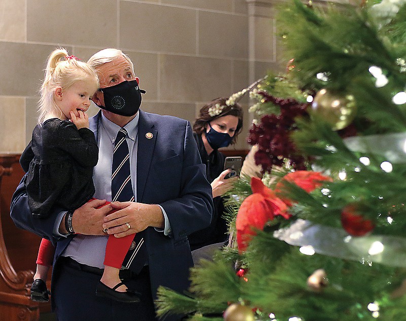 Gov. Mike Parson holds Clara Hahn, 3, as they gaze Thursday at the Christmas tree in front of the governor's office in the state Capitol. Parson circled the tree with Clara, pointing out the various decorations and asking her questions about what she liked about the holiday season.