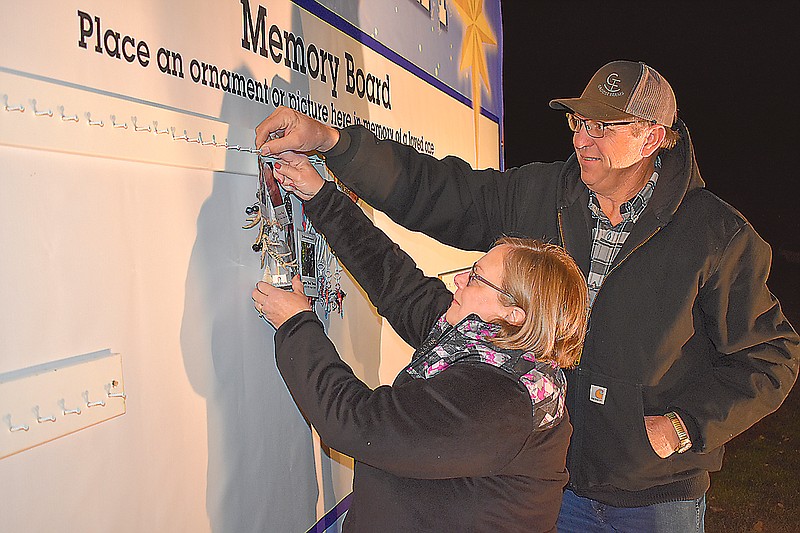 Debbie and Chris Groose, of Eugene, hang items Sunday in memory of loved ones at the Jack's Memory Tree event at Hawthorn Memorial Gardens. Throughout the holiday season, people are invited to come by the cemetery to place a special ornament or picture in honor of a loved one.
