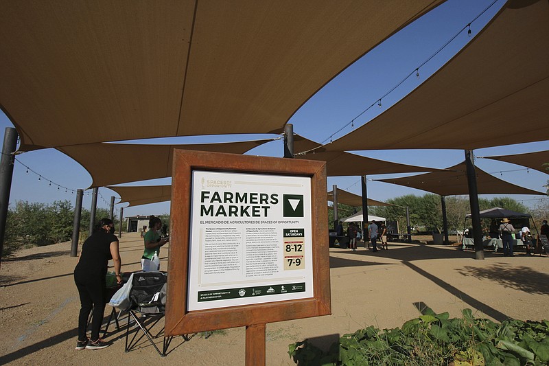 Several local vendors set up their booths at Spaces of Opportunity in south Phoenix for its weekly farmers market Tuesday, Oct. 17, 2020. Arizona nonprofits have joined other groups around the U.S. working to bring fresh produce and healthy food options to residents in low-income and racially and ethnically diverse neighborhoods. Spaces of Opportunity, a collective of Phoenix-based organizations, was founded on the idea the community could come together to grow local fruits and vegetables, assist local farmers with land and income, and educate its residents about food security.  (AP Photo/Cheyanne Mumphrey)