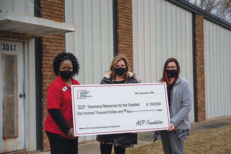 From left, Marcia Austin, Jennifer Harland and Jennifer Lewis hold a grant check presented Tuesday to Texarkana Resources for the Disabled by American Electric Power Foundation outside of the building they will renovate with the grant money.