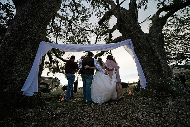 Emily and Taylor Pascale pose for photos after getting married outside the home of Taylor's parents, Friday, Dec. 4, 2020, in Grand Lake, La., which was heavily damaged from Hurricanes Laura and Delta. (AP Photo/Gerald Herbert)