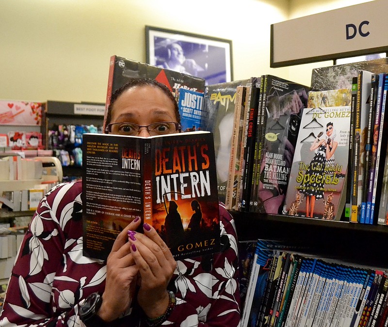 Local author D.C. Gomez poses with her first book, "Death's Intern." (PHOTO BY KATE STOW)