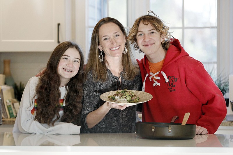 From left, Abigail Zinn, 13, Stephanie Zinn (mom) with her ground beef with broccoli and Cody Zinn, 16. Stephanie is among the coordinators and contributors to a cookbook called "Pots and Pandemic: Cooking in Quarantine," that includes recipes and reflections about coping with the pandemic by getting busy in the kitchen. The book is a fundraising project of Temple M'kor Shalom in Cherry Hill. Zinn was photographed in Haddonfield, N.J. (Elizabeth Robertson/The Philadelphia Inquirer/TNS)