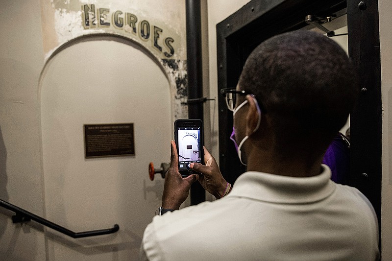 In this  Monday, Nov. 17, 2020 file photo, Dannion McLendon takes a photo of the historical marker placed and sign that reads "NEGROES" at the Ellis County Courthouse in Waxahachie, Texas. Controversy over a segregation-era "Negroes" sign in a Texas courthouse has taken an unusual turn after Ellis County Judge Todd Little, a top county official was identified as a suspect in a criminal investigation into the historical sign being vandalized. (Lynda M. Gonzalez/The Dallas Morning News via AP, File)