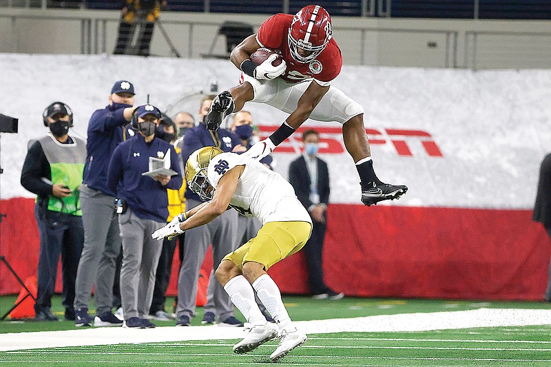 Alabama running back Najee Harris hurdles Notre Dame cornerback Nick McCloud as he carries the ball for a long gain in the first half of the Rose Bowl on Friday in Arlington, Texas.