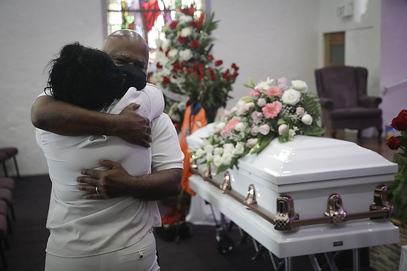 FILE - In this July 21, 2020, file photo, Darryl Hutchinson, facing camera, is hugged by a relative during a funeral service for Lydia Nunez, who was Hutchinson's cousin at the Metropolitan Baptist Church in Los Angeles. Nunez died from COVID-19. Southern California funeral homes are turning away bereaved families because they're running out of space for the bodies piling up during an unrelenting coronavirus surge. (AP Photo/Marcio Jose Sanchez, File)