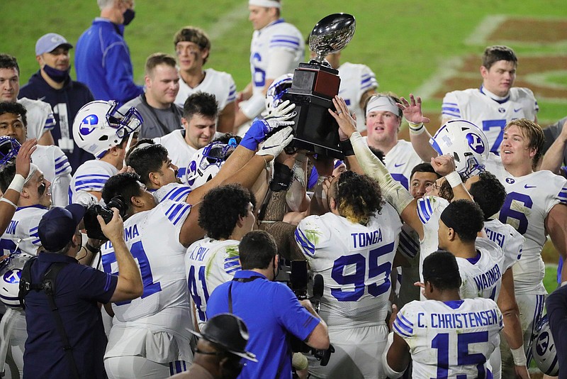 BYU players hold the championship trophy after defeating UCF in the Boca Raton Bowl NCAA college football game at FAU Stadium in Boca Raton, Fla. Tuesday, Dec. 22, 2020.(Al Diaz/Miami Herald via AP)