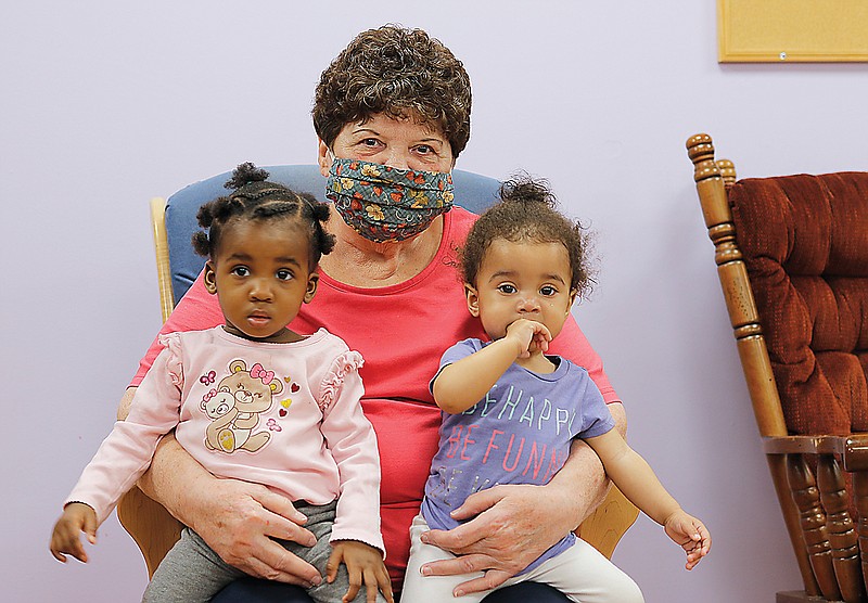 Carolyn Fluegel sits in a rocking chair with Harmony and Harmony's cousin, Ava, both 1, on Wednesday at Little Explorers Discovery Center. Fluegel has been volunteering at the daycare center for 14 years. 