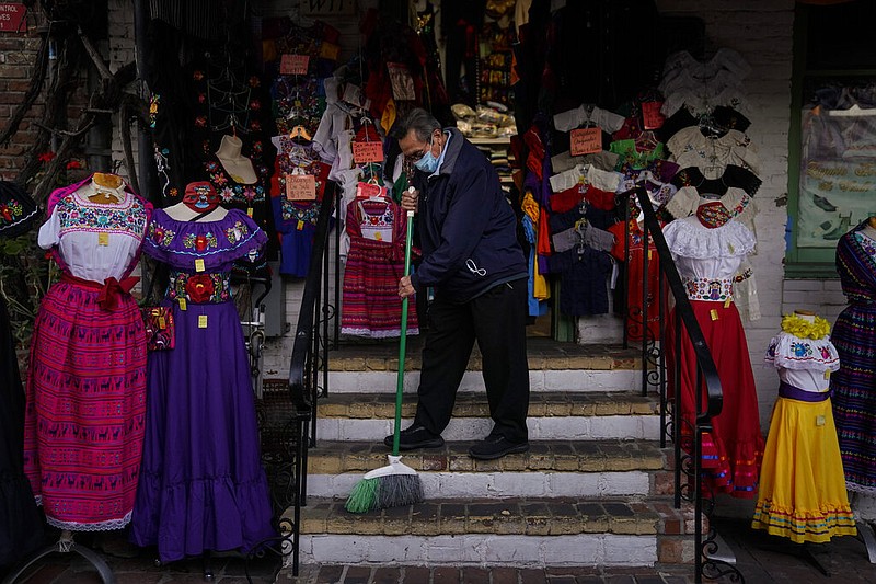 Victor Flores, 66, a third-generation owner of a gift shop, sweeps the steps of his store on Olvera Street in downtown Los Angeles, Wednesday, Dec. 16, 2020. Millions of business owners are about to get additional help as they weather the coronavirus outbreak. The Small Business Administration and the Treasury Department are reviving the Paycheck Protection Program five months after its first two rounds of funding ended.