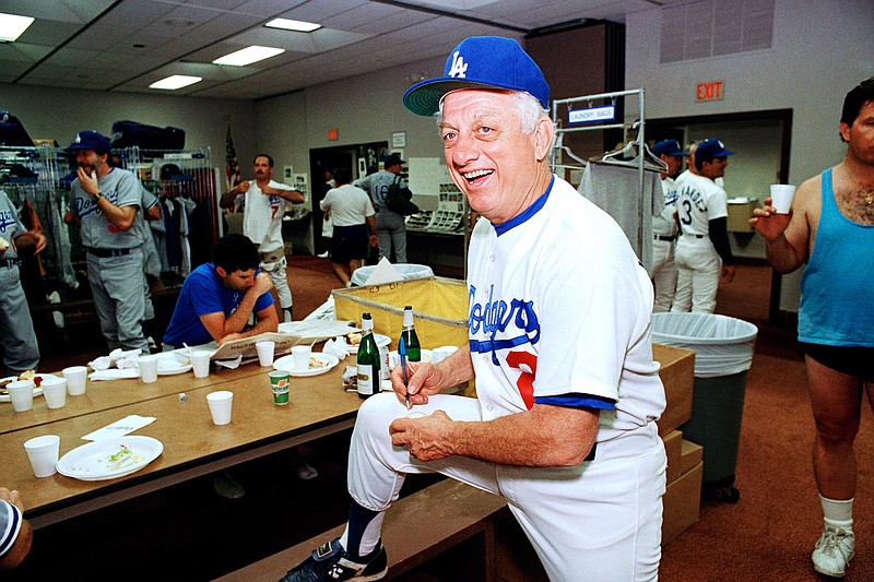 Los Angeles Dodgers manager Tommy Lasorda autographs a baseball in the Dodgertown locker-room in Vero Beach, Fla., in this Wednesday, Feb. 15, 1990, file photo. Tommy Lasorda, the fiery Hall of Fame manager who guided the Los Angeles Dodgers to two World Series titles and later became an ambassador for the sport he loved during his 71 years with the franchise, has died. He was 93. The Dodgers said Friday, Jan. 8, 2021, that he had a heart attack at his home in Fullerton, California. Resuscitation attempts were made on the way to a hospital, where he was pronounced dead shortly before 11 p.m. Thursday.  (AP Photo/Richard Drew, File)