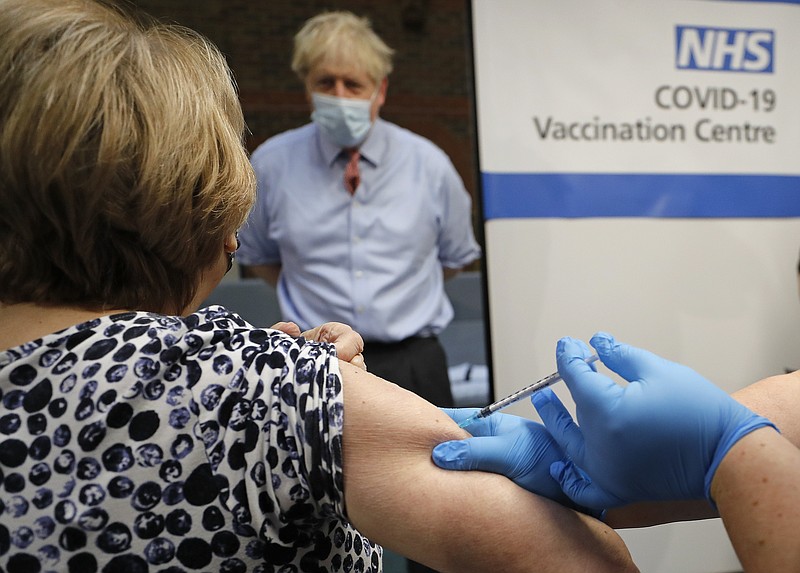 FILE - In this Tuesday, Dec. 8, 2020 file photo, British Prime Minister Boris Johnson watches as nurse Rebecca Cathersides administers the Pfizer-BioNTech COVID-19 vaccine to Lyn Wheeler at Guy's Hospital in London. Britain races to vaccinate more than 15 million people by mid-February, and in an effort to ensure vaccines get to the right places at the right times, along with the syringes, alcohol swabs and protective equipment needed to administer them, the government has called in the army. (AP Photo/Frank Augstein, Pool, File)