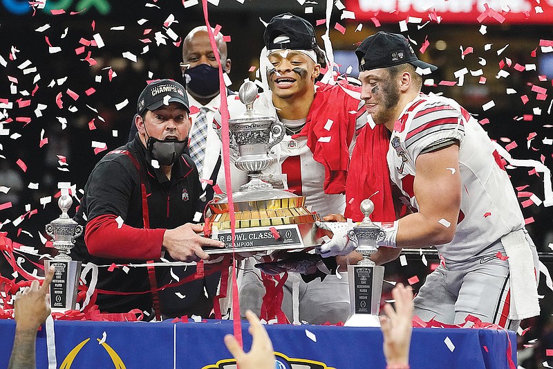 (From left) Ohio State coach Ryan Day, quarterback Justin Fields and linebacker Tuf Borland hold the Sugar Bowl trophy after the team's win against Clemson last week in New Orleans.