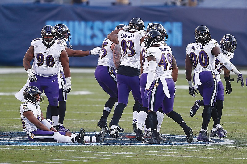 Ravens players sit and stand on the Titans' logo at midfield after Ravens cornerback Marcus Peters intercepted a pass late in Sunday's AFC wild-card game in Nashville, Tenn.