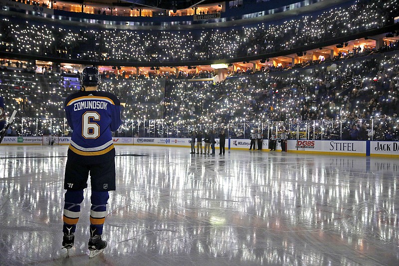 In this Dec. 1, 2017, file photo, Joel Edmundson of the Blues pauses as fans use their phones to light up Scottrade Center during a ceremony as part of a league-wide cancer awareness campaign before a game against the Kings in St. Louis.