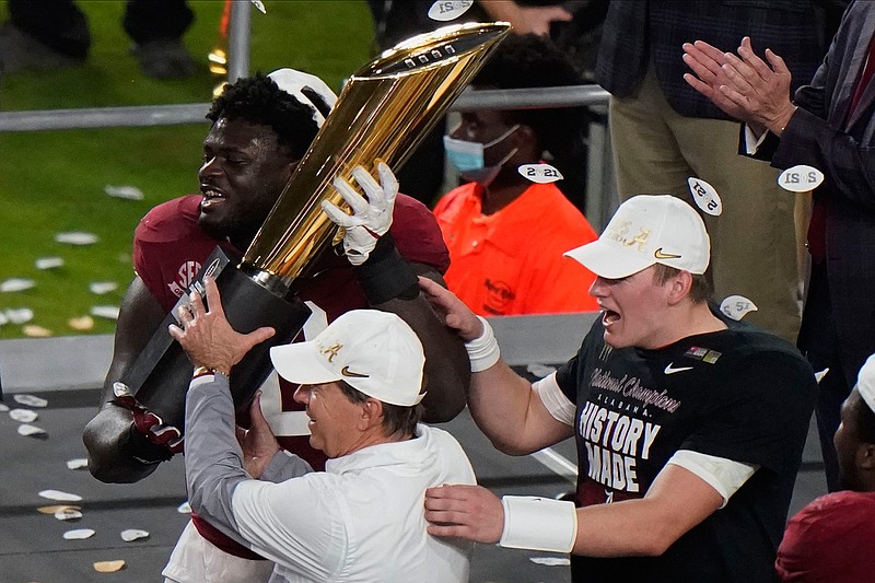 Alabama head coach Nick Saban and offensive lineman Alex Leatherwood hold the trophy after their win against Ohio State in an NCAA College Football Playoff national championship game, Tuesday, Jan. 12, 2021, in Miami Gardens, Fla. Alabama won 52-24. (AP Photo/Wilfredo Lee)