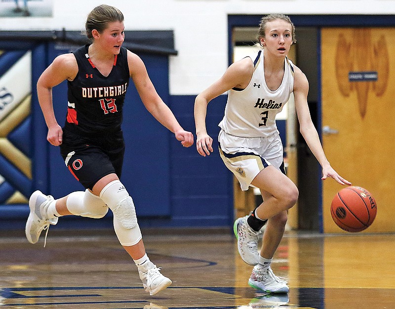 Helias guard Mikah Edwards drives up the court while chased by Owensville guard Katelyn Landolt during Tuesday's game at Rackers Fieldhouse.
