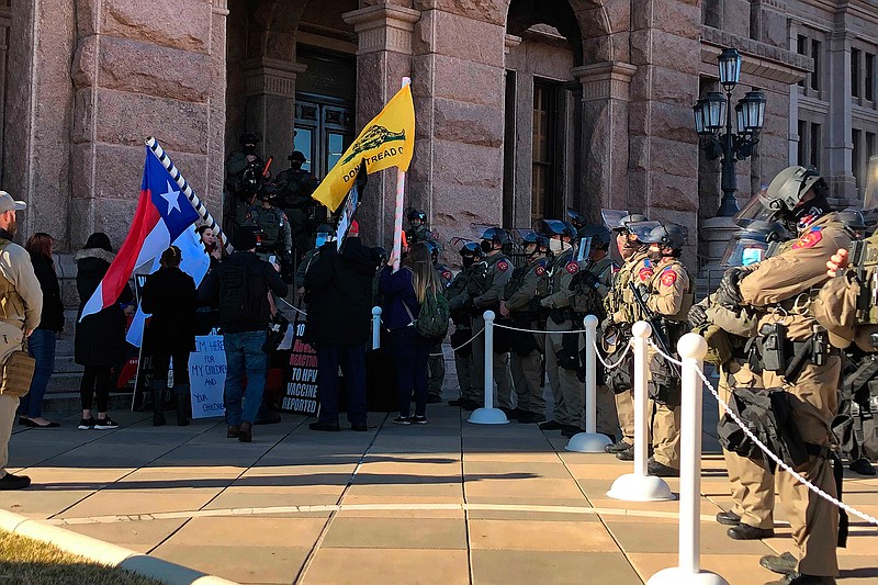 Protesters against COVID-19 vaccines face Texas state troopers wearing riot gear outside the Capitol in Austin, Texas, on Tuesday, Jan. 12, 2021, the opening day of the legislative session. The Texas Department of Public Safety has increased its presence at the state Capitol after last week's deadly attack on the U.S. Capitol by supporters of President Donald Trump. The FBI also has warned of plans for armed protests at all 50 state capitals and in Washington, D.C., in the days leading up to President-elect Joe Biden's inauguration. (AP Photo/Jim Vertuno)
