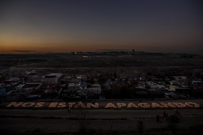 A protest with candles reading in Spanish: "'You are extinguishing our lights" in reference to cutting off the electricity at the Canada Real shanty town, outside Madrid, Spain, Tuesday, Jan. 5, 2021. As a record snowfall blanketed much of Spain this week and temperatures plunged below zero, few suffered the consequences as severely as the thousands of residents of the La Canada Real Galiana mega shantytown outside Madrid, long a major embarrassment for Spain. (AP Photo/Manu Fernandez)