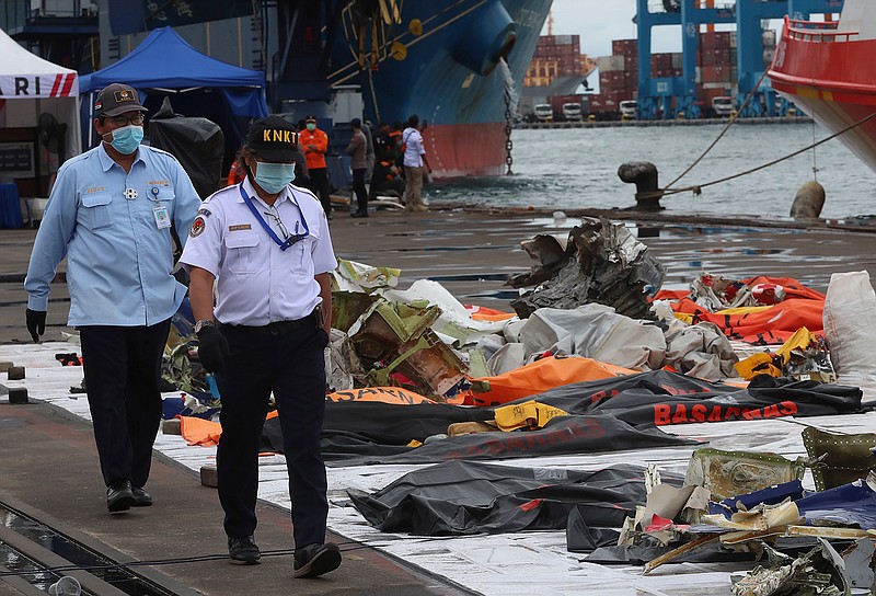 Indonesian National Transportation Safety Committee (KNKT) investigators walk near debris found in the waters around the location where a Sriwijaya Air passenger jet crashed, at the search and rescue command center at Tanjung Priok Port in Jakarta, Indonesia, Indonesia, Wednesday, Jan. 13, 2021. Divers looking for the crashed plane's cockpit voice recorder were searching in mud and plane debris on the seabed between Indonesian islands Wednesday to retrieve information key to learning why the Sriwijaya Air jet nosedived into the water over the weekend. (AP Photo/Achmad Ibrahim)