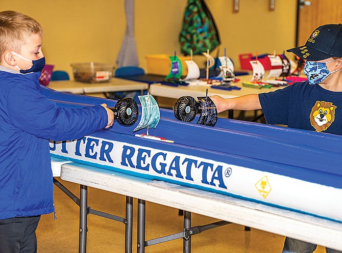 Cub Scouts from Pack 9, of Holts Summit, use fans Saturday to blow their boats down the water track at the pack's annual Raingutter Regatta.