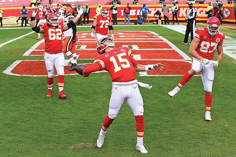 Chiefs quarterback Patrick Mahomes throws the ball into the stands while being cheered on by center Austin Reiter (left) and tight end Travis Kelce (right) after scoring against the Browns during Sunday's AFC divisional round game at Arrowhead Stadium in Kansas City.