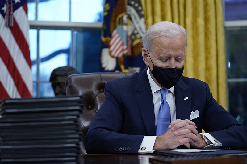 President Joe Biden pauses as he signs his first executive orders in the Oval Office of the White House on Wednesday, Jan. 20, 2021, in Washington. (AP Photo/Evan Vucci)