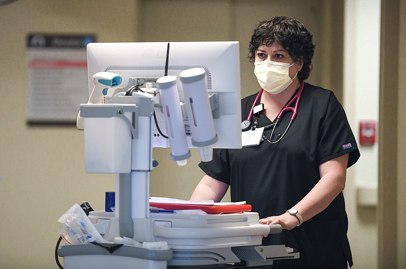 In this January 2021 photo, LaCrissa Craig, as a registered nurse at Capital Region Medical Center, views her computer on wheels as she checks on patient care.