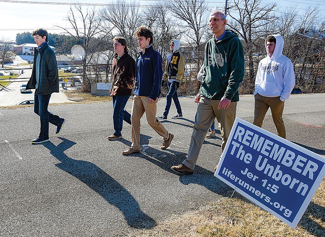 Students in Mark Rehagen's religion class recite the Rosary as they walk Friday with Rehagen along the track at Helias Catholic High School. Several groups of students participated in the walk, meant to coincide with the national March for Life, which was held virtually this year. In addition, Friday was a dress-down day at the school where students could pay to be out of uniform. More than $900 was raised, which will go to the Pregnancy Help Center.