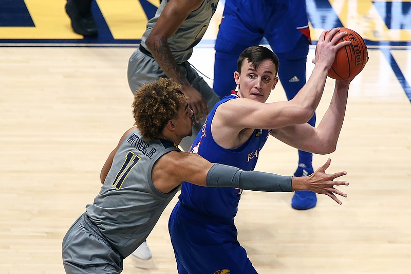 Kansas guard Mitch Lightfoot (44) passes while defended by West Virginia forward Emmitt Matthews Jr. (11) during the second half of an NCAA college basketball game Saturday, Feb. 6, 2021, in Morgantown, W.Va. (AP Photo/Kathleen Batten)