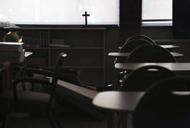 FILE - In this Monday, June 8, 2020 file photo, a cross sits in the window of an empty classroom at Quigley Catholic High School in Baden, Pa. On Monday, Feb. 8, 202, Catholic education officials reported that enrollment in Roman Catholic schools in the United States dropped 6.4% from the previous academic year amid the pandemic and economic stresses — the largest single-year decline in at least five decades. (AP Photo/Jessie Wardarski)