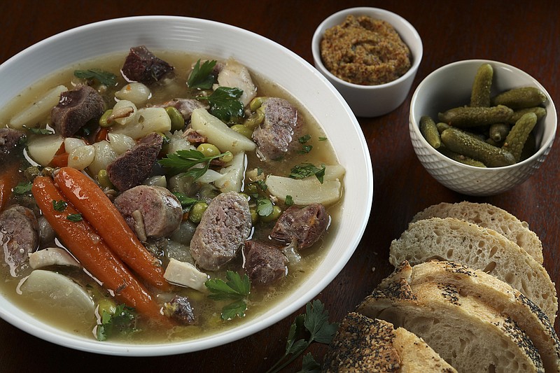Pot au feu (boiled meats dinner) is served with accompaniments like carrots, pearl onions, fresh herbs, pickles, mustard. (Abel Uribe/Chicago Tribune/TNS) 