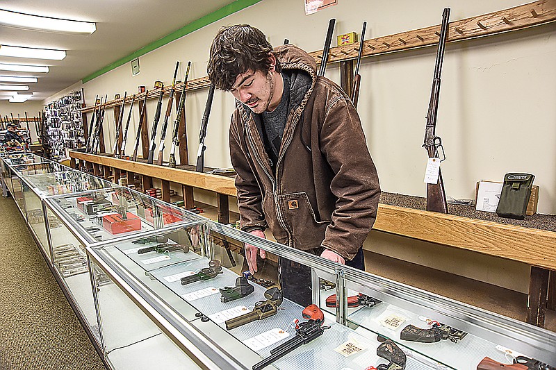 Jacob Laughlin, owner of Bogg's Creek, Inc. on Eastland Drive pulls one of the guns from the shelf of his east side Jefferson City store. Laughlin said a shipment of ammo usually sells out as soon as it's received.
