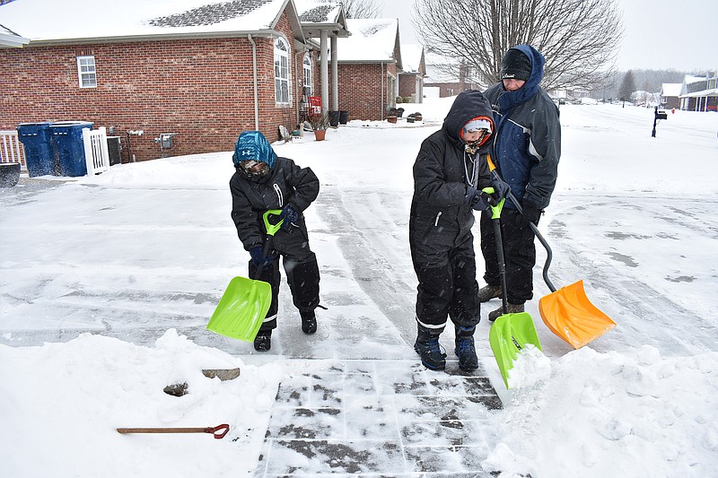 Gerry Tritz/News Tribune
From left, Brock Ralston, 7, and older brother Brenden, 10, help their father, T.J. Ralston, shovel snow off their driveway Sunday afternoon amid snow flurries and a temperature of 1 degree.