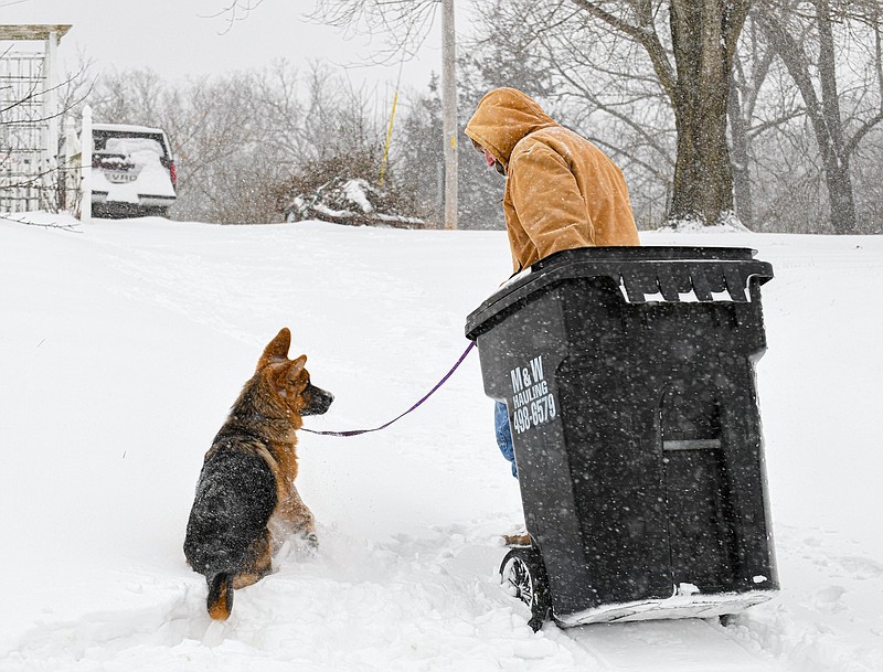 A Cole County resident and his dog retrieve the trash receptacle from the bottom of the driveway amid freezing temperatures and snow Monday, Feb. 15, 2021.