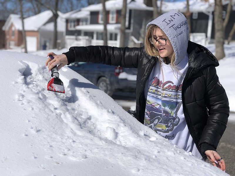 Grace Lecure clears the windshield of her car of ice and snow prior to driving on the west side of Jefferson City on Tuesday, Feb. 16, 2021.