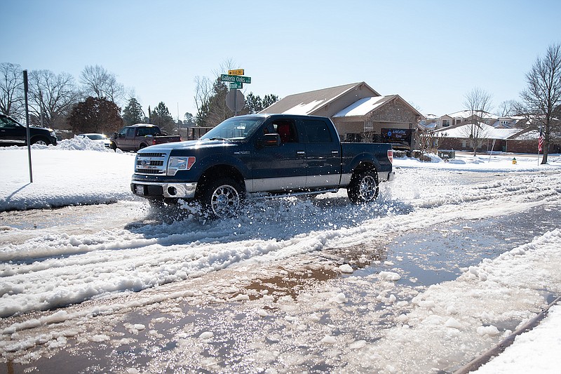 A truck drives through the layers of snow and ice that melted Friday on Galleria Oaks Drive in Texarkana, Texas. The melt is expected to freeze over as temperatures drop below freezing again Friday night.
