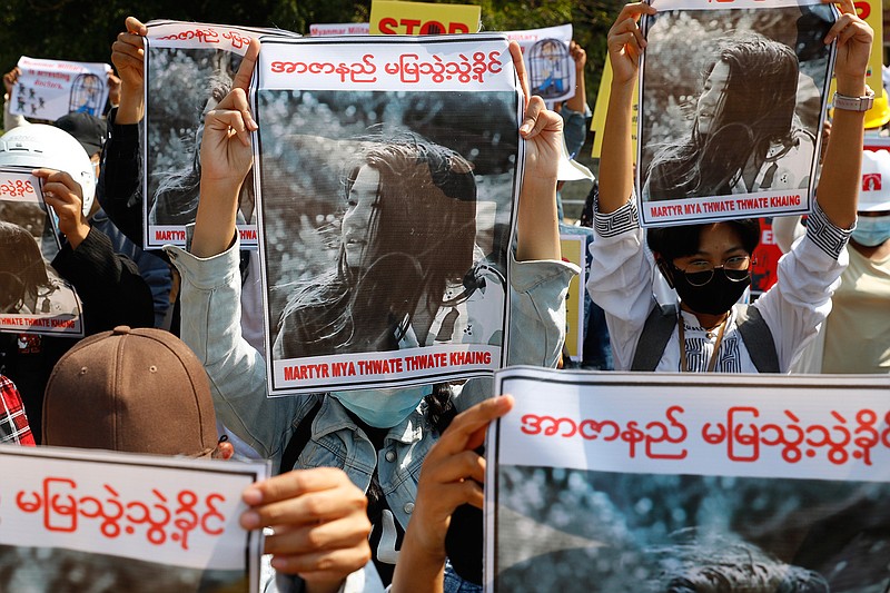 In this Feb. 14, 2021, file photo, Mandalay University graduates hold posters with images of Mya Thwet Thwet Khine, a young woman who was shot in the head by police during a protest on Feb. 9 in Naypyitaw, during an anti-coup protest in Mandalay, Myanmar. Thewoman shot by police during a protest against the military's takeover of power died Friday morning, Feb. 19, 2021, her brother said. (AP Photo, File)