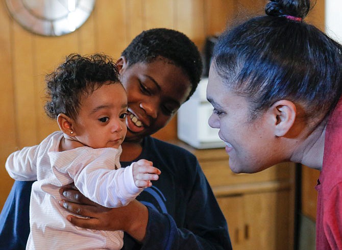 Megan Criddle, right, talks to her 7-month-old daughter, Hope, as the baby is held by James Criddle Jr., 11, on Friday afternoon in their home. A year ago, the Criddles were living in a one-bedroom apartment, which was damaged by the tornado. Now, thanks to Catholic Charities and the United Way of Central Missouri's 211 help line, the family of eight lives in a home on Adams Street.