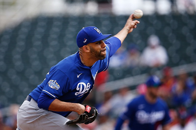 In this March 2, 2020, file photo, Los Angeles Dodgers starting pitcher David Price throws against the Cincinnati Reds during the first inning of a spring training baseball game in Goodyear, Ariz. Price, Buster Posey, Marcus Stroman and more than a dozen other players who opted out of the pandemic-shortened 2020 season get back to work this week. They not only will have to deal with rust but the demands of MLB's coronavirus safety protocols.   (AP Photo/Ross D. Franklin, File)