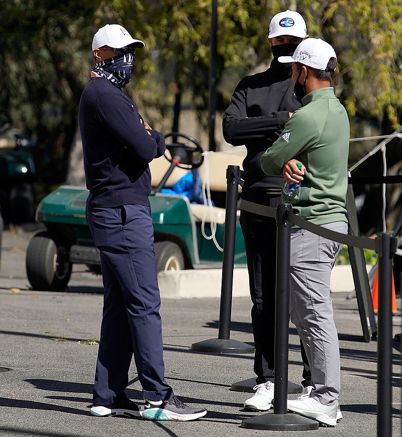 From left, Tiger Woods, Dustin Johnson and Xander Schauffele talk after high winds suspended play during the third round of the Genesis Invitational golf tournament at Riviera Country Club, Saturday, Feb. 20, 2021, in the Pacific Palisades area of Los Angeles. (AP Photo/Ryan Kang)