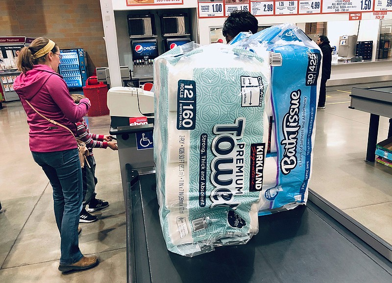 In this March 23, 2020 file photo, a shopper pays for packages of toilet paper and hand towels at a Costco warehouse in Lone Tree, Colo. As Americans stayed home and ordered online during the lockdowns of 2020, our homes became filled with all sorts of purchases: toilet paper, crafts and plenty of board games. But as time wears on, what do you do if you find yourself with too much stuff? There are some easy ways to sell or donate the things you have in your house. (AP Photo/David Zalubowski, File)