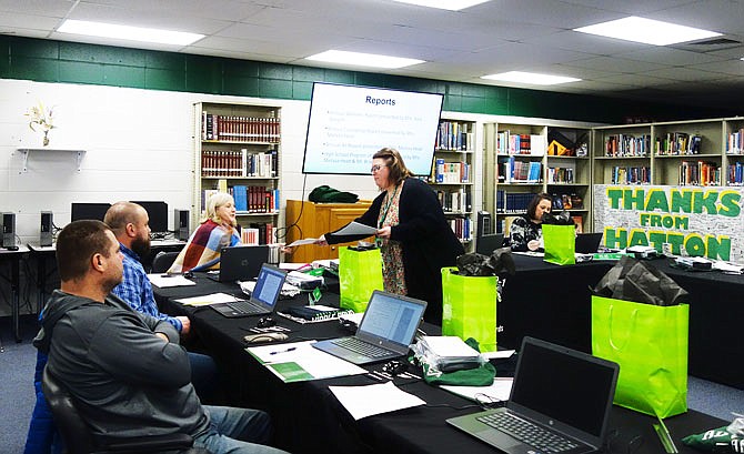 Melissa Head, counselor at North Callaway High School, passes a report around to members of the North Callaway Board of Education during Thursday's meeting.