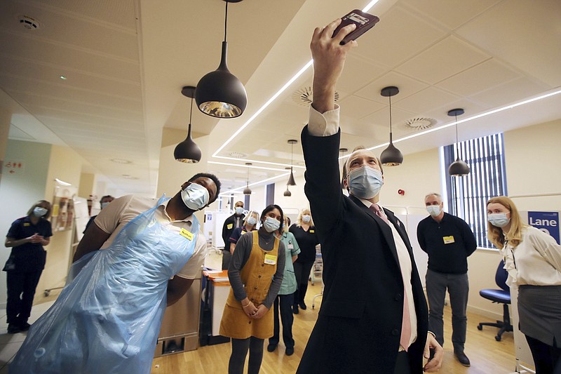 FILE - In this Wednesday, Feb. 17, 2021 file photo, Britain's Health Secretary Matt Hancock takes a selfie with the vaccine hub staff during a visit to the Queen Elizabeth Hospital in Birmingham, England, to thank volunteers undertaking clinical trials for the COVID-19 vaccinations. The British government says it aims to give every adult in the country a first dose of coronavirus vaccine by July 31, a month earlier than its previous target. In addition, the goal is for everyone over 50 or with an underlying health condition to get a shot by April 15, rather than the previous target of May 1.  (Molly Darlington/Pool via AP, File)