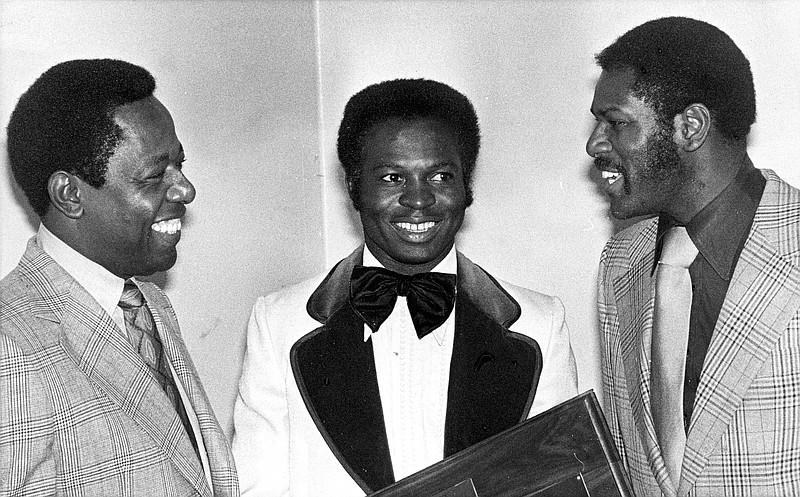 FILE - In this Jan. 28, 1975, file photo, three of the tops in baseball, from left, Hank Aaron, Lou Brock and Bob Gibson talk at an event where they were honored by St. Louis baseball writers in St. Louis. Aaron was honoroed for his 733 home runs and breaking Babe Ruth's record; Brock for his 118 stolen bases in one season and Bob Gibson for passing the National League strikeout record. In the 1970s, players of color finally stepped into an unfettered spotlight, the reserve clause ended, free agency began and the players' union found its voice. (AP Photo/File)